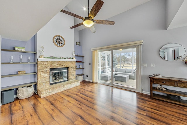 living area featuring high vaulted ceiling, a brick fireplace, wood finished floors, and baseboards