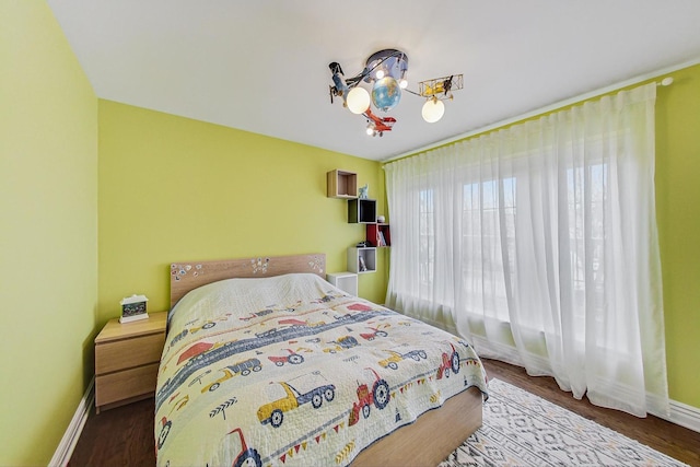 bedroom featuring a notable chandelier, baseboards, and wood finished floors