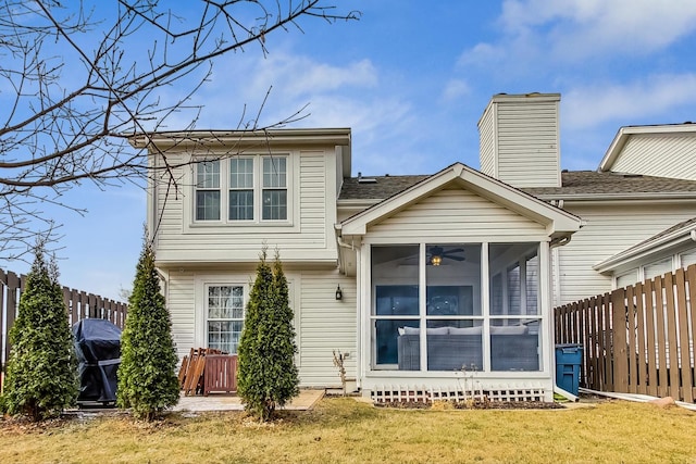 back of property featuring a sunroom, a fenced backyard, a chimney, and a lawn