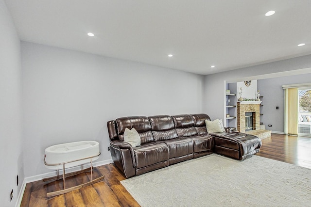 living room with a fireplace, baseboards, wood finished floors, and recessed lighting