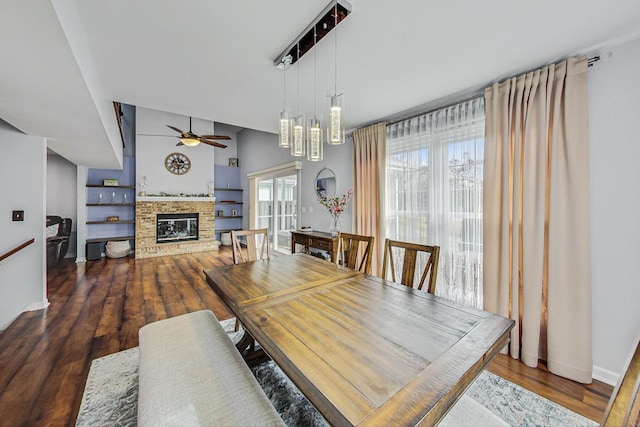 dining area with a fireplace, wood finished floors, a ceiling fan, and baseboards