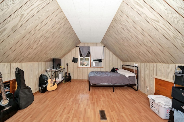 bedroom featuring lofted ceiling, visible vents, wooden walls, and wood finished floors