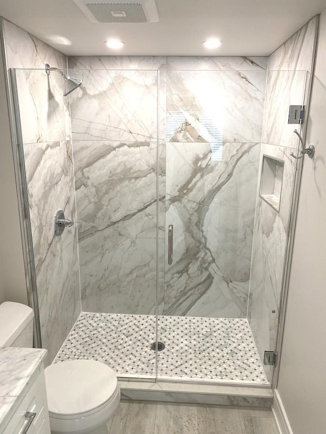 full bathroom featuring a marble finish shower, visible vents, toilet, vanity, and wood finished floors