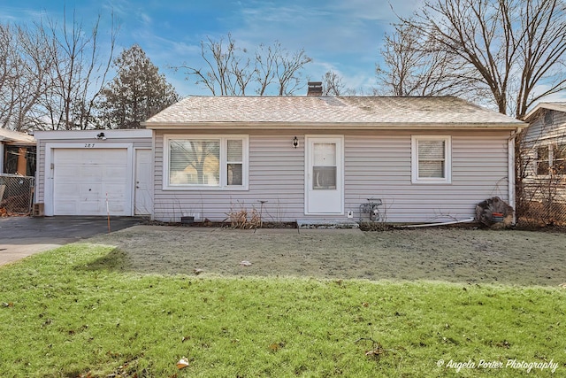 single story home featuring a front lawn, an attached garage, driveway, and a chimney