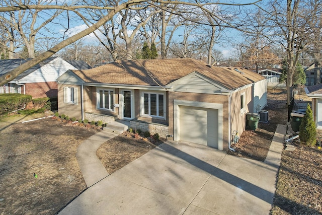 ranch-style house featuring central air condition unit, roof with shingles, concrete driveway, a garage, and brick siding