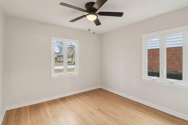 empty room featuring a ceiling fan, baseboards, and light wood finished floors