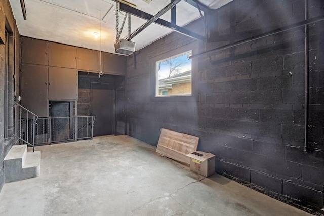 garage with a garage door opener and concrete block wall