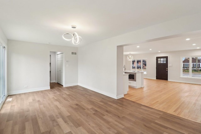 spare room featuring baseboards, an inviting chandelier, and light wood-style flooring