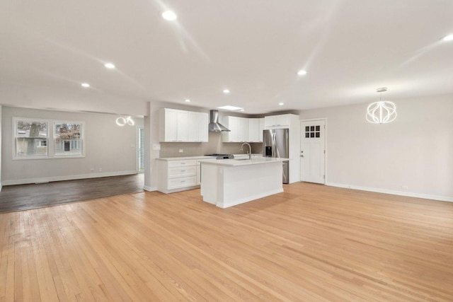 kitchen featuring stainless steel fridge with ice dispenser, open floor plan, light wood-type flooring, light countertops, and wall chimney exhaust hood