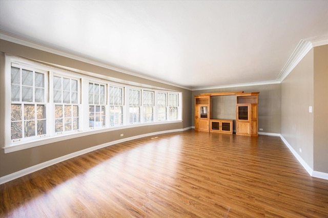 unfurnished living room with baseboards, wood finished floors, and ornamental molding