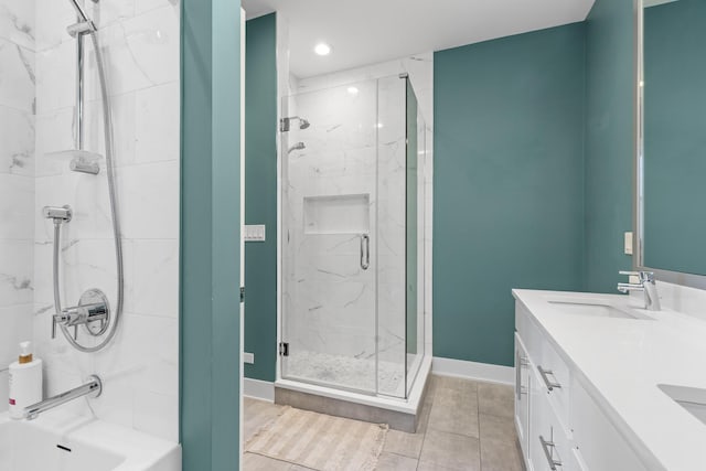 full bath with a marble finish shower, double vanity, baseboards, and a sink