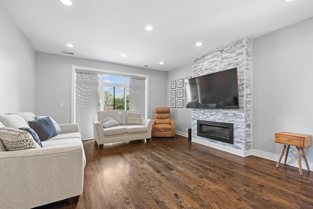 living area featuring dark wood-style floors, visible vents, baseboards, recessed lighting, and a stone fireplace