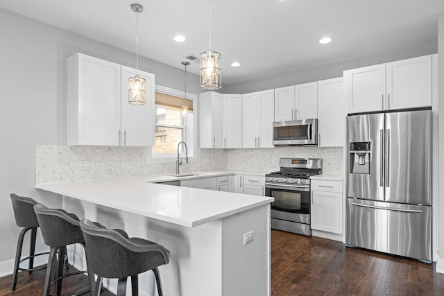 kitchen with decorative backsplash, appliances with stainless steel finishes, a peninsula, white cabinetry, and a sink