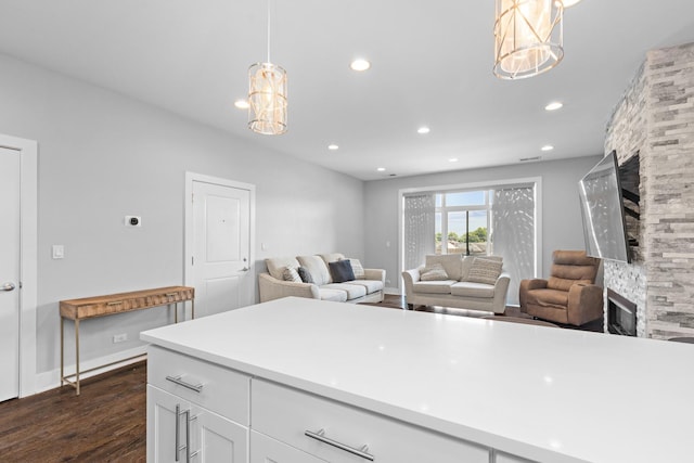 kitchen with dark wood-type flooring, pendant lighting, recessed lighting, a stone fireplace, and white cabinets