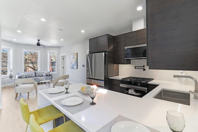 kitchen with stainless steel appliances, recessed lighting, light countertops, light wood-style floors, and a sink