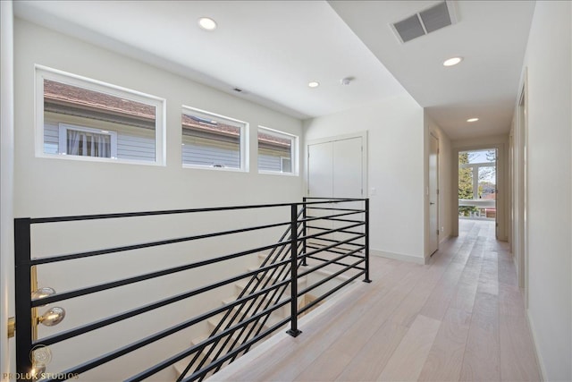 hall with light wood-type flooring, visible vents, an upstairs landing, and recessed lighting