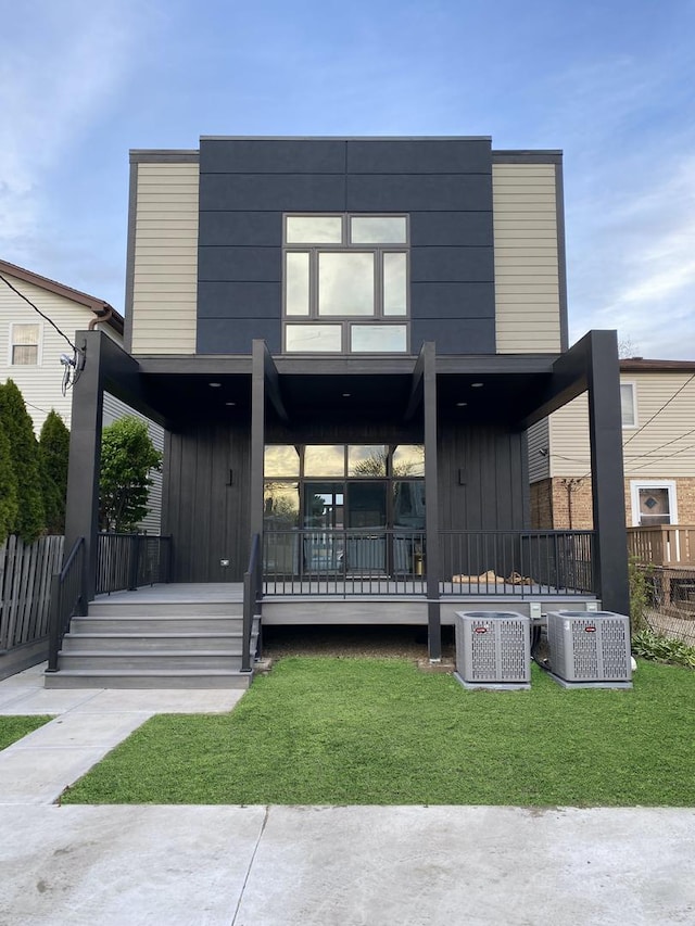 view of front of home featuring board and batten siding, a front lawn, and central air condition unit