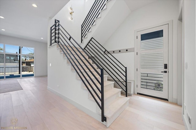 staircase with baseboards, wood finished floors, and recessed lighting