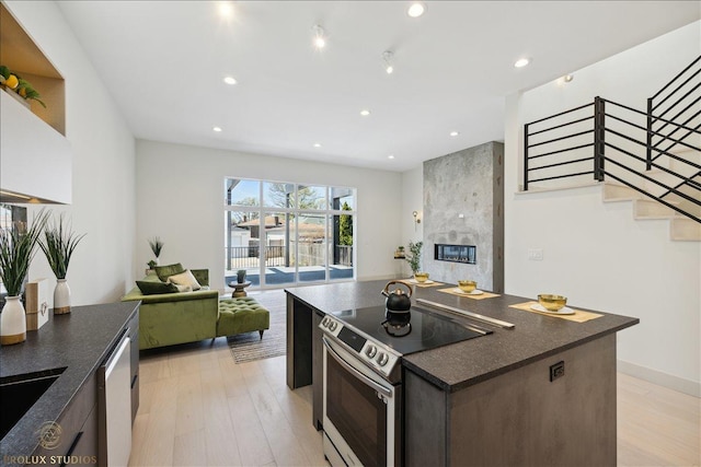 kitchen featuring dark countertops, light wood finished floors, stainless steel appliances, and open floor plan