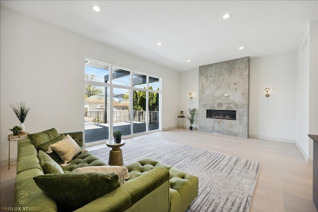 living room with recessed lighting, baseboards, light wood-style flooring, and a tiled fireplace