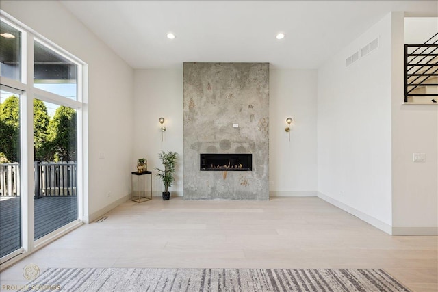 unfurnished living room with recessed lighting, a fireplace, baseboards, and wood finished floors