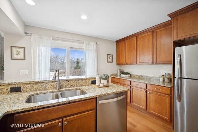 kitchen featuring appliances with stainless steel finishes, brown cabinetry, and a sink