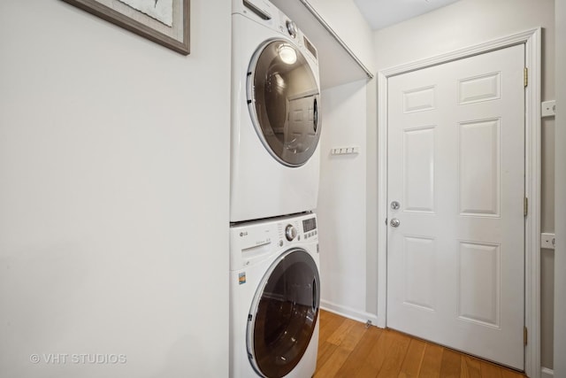 laundry room with light wood-type flooring, laundry area, and stacked washer / dryer