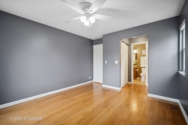 unfurnished bedroom featuring light wood finished floors, visible vents, ensuite bathroom, a ceiling fan, and baseboards