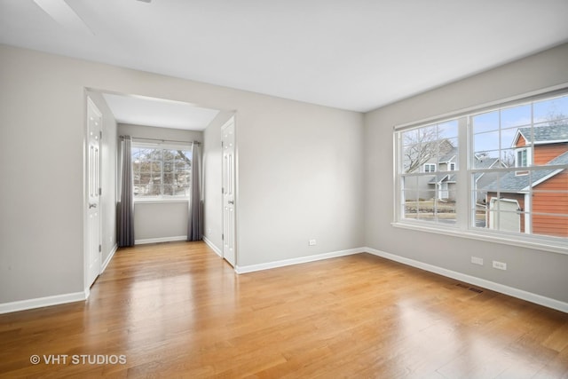 unfurnished room with visible vents, light wood-style flooring, and baseboards