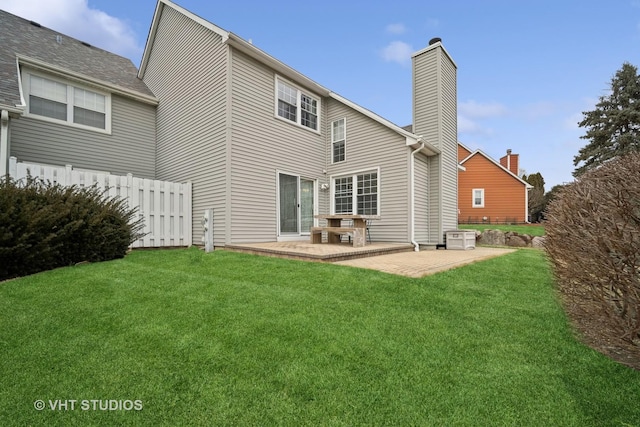 back of house with a patio area, a chimney, fence, and a lawn