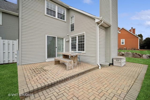 back of property featuring a patio area, a chimney, and fence