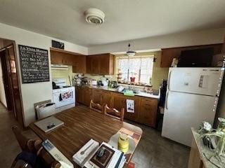 kitchen with exhaust hood, light countertops, brown cabinets, range, and freestanding refrigerator