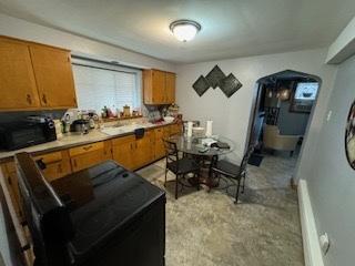 kitchen featuring arched walkways, brown cabinets, and light countertops