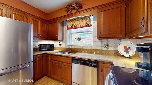 kitchen with stainless steel appliances, backsplash, a sink, and brown cabinetry