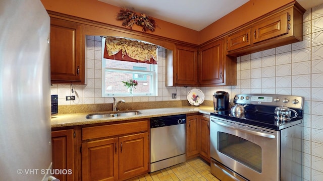 kitchen with stainless steel appliances, brown cabinets, a sink, and backsplash