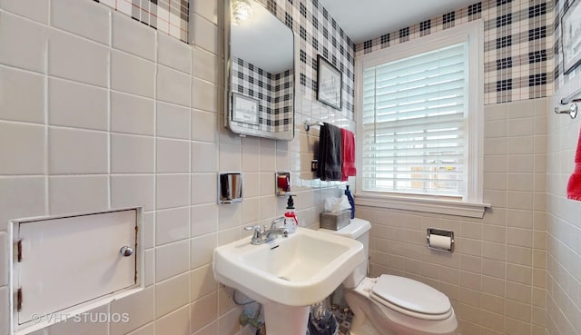 bathroom with a sink, tile walls, and toilet