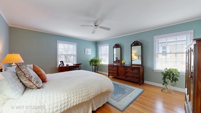 bedroom with light wood-style floors, crown molding, baseboards, and ceiling fan