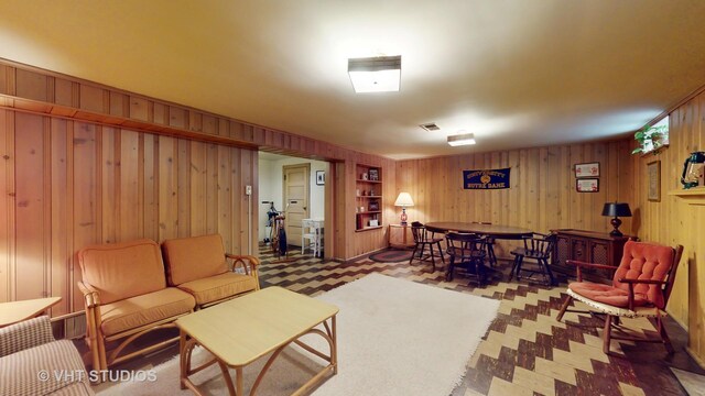 living room with wood walls, visible vents, and tile patterned floors