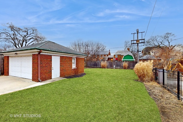 view of yard with a garage, an outbuilding, concrete driveway, and fence