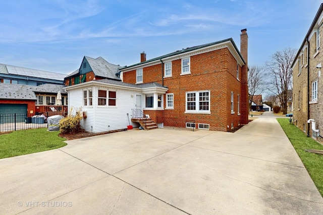 rear view of house with brick siding, fence, and a chimney