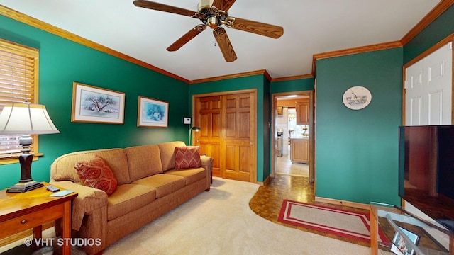 carpeted living area with ornamental molding and a ceiling fan