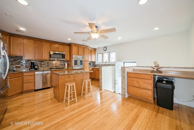 kitchen featuring backsplash, a center island, a breakfast bar, light wood-type flooring, and appliances with stainless steel finishes