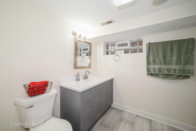 bathroom with visible vents, toilet, vanity, and baseboards