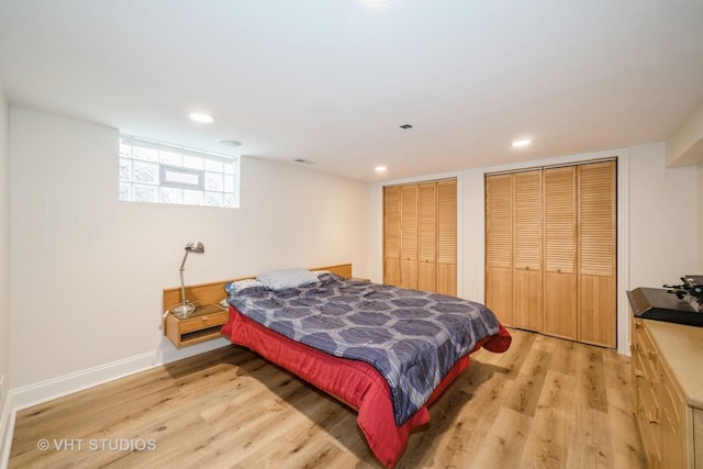 bedroom featuring two closets, baseboards, light wood-style floors, and recessed lighting