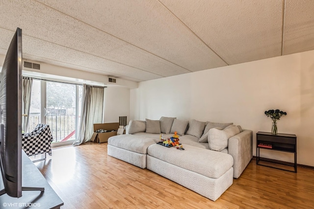 living area with light wood-type flooring, visible vents, and baseboards