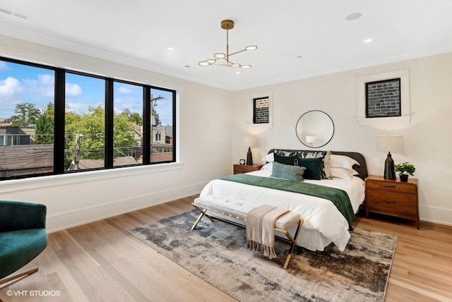 bedroom featuring visible vents, baseboards, light wood-style floors, and crown molding