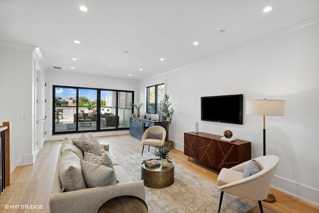 living room featuring recessed lighting, baseboards, light wood-style floors, and crown molding