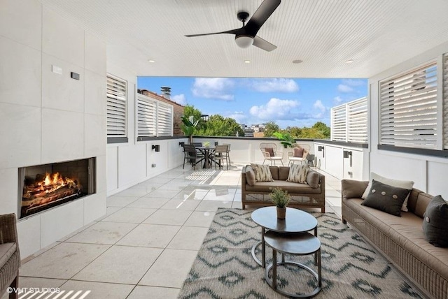 living room featuring light tile patterned flooring, a tile fireplace, and a ceiling fan