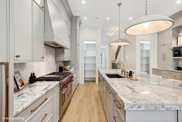 kitchen with a large island, a sink, tasteful backsplash, range with two ovens, and custom exhaust hood