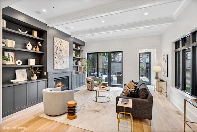 living room featuring light wood finished floors, beamed ceiling, built in features, recessed lighting, and a fireplace